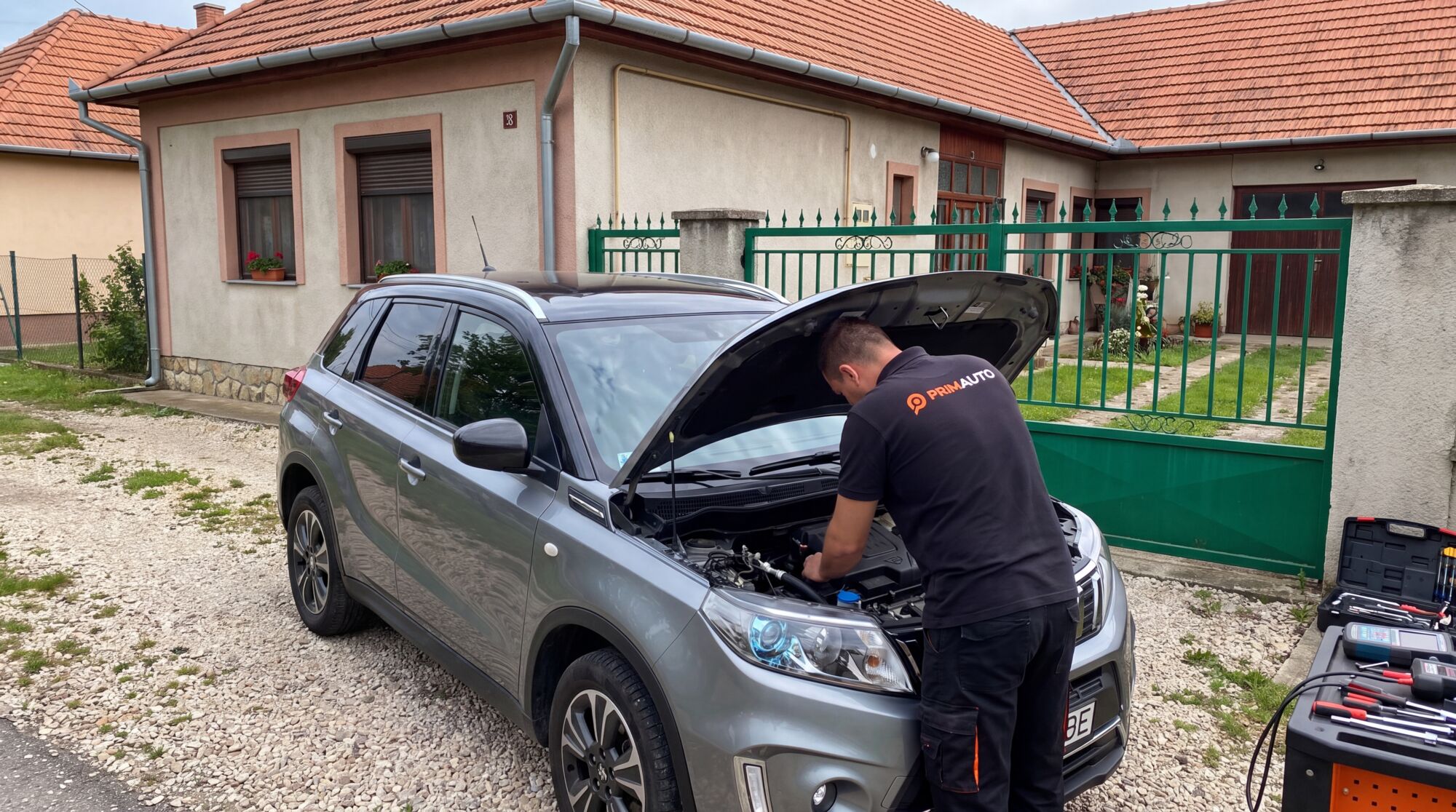 PRIMAUTO szakember egyedül vizsgál egy Suzuki Vitarát egy családi ház előtt